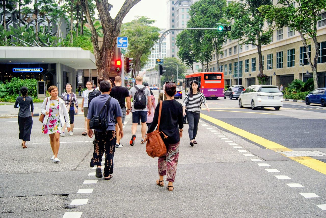 People crossing a busy intersection in Singapores urban landscape.