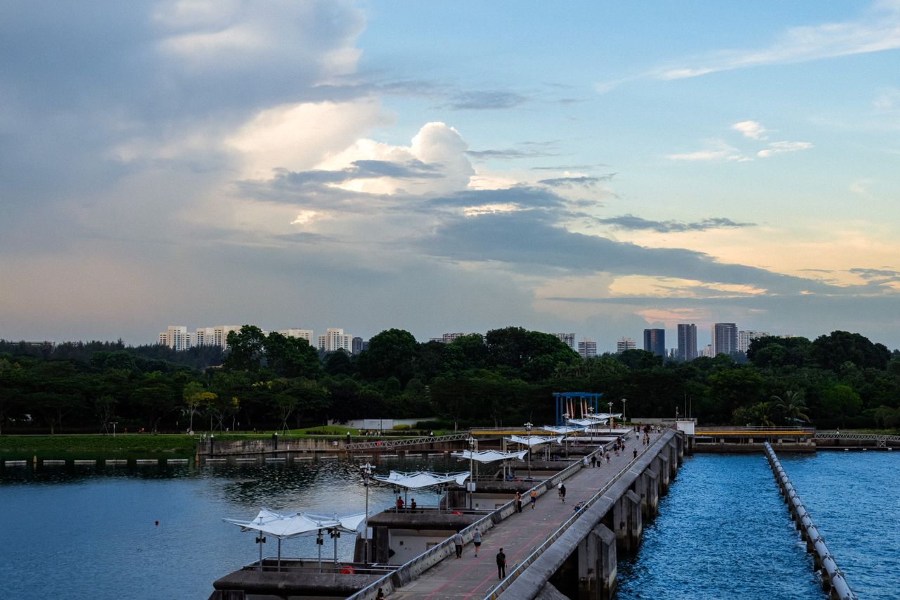 A scenic view of a jetty leading towards the skyline, set against a dramatic sky in Singapore.